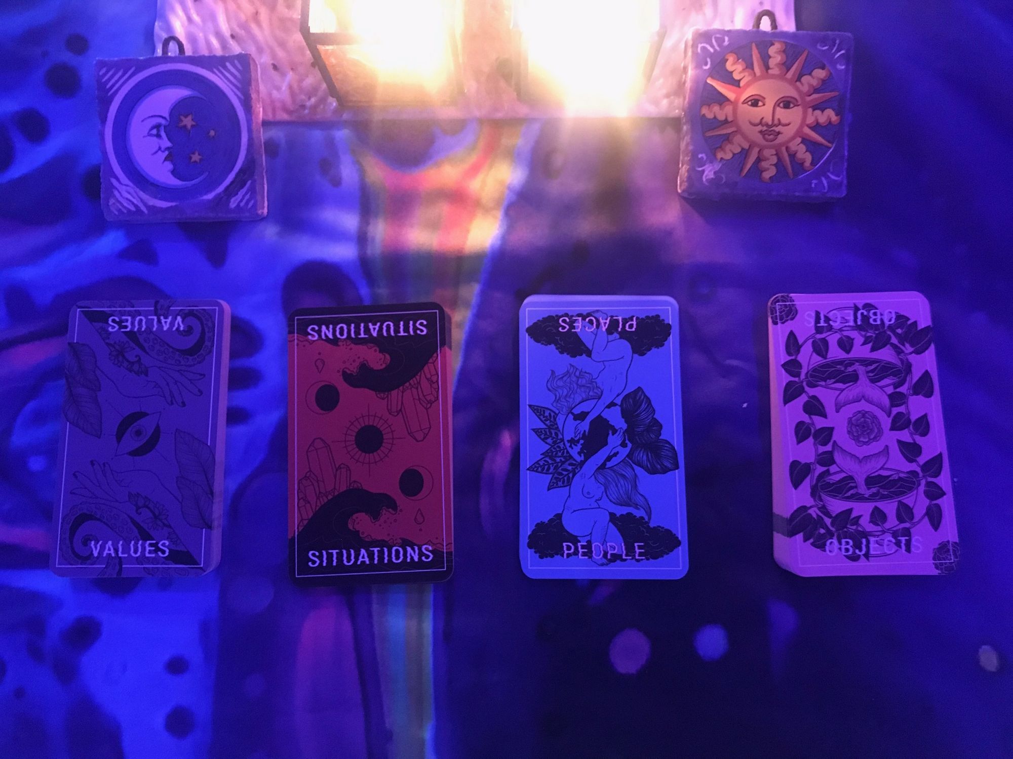 Four cards, with the words Values, Situations, Places, and Objects.  Above them, two small ceramic tiles with a moon on the left and a sun on the right, and candlelight between them.